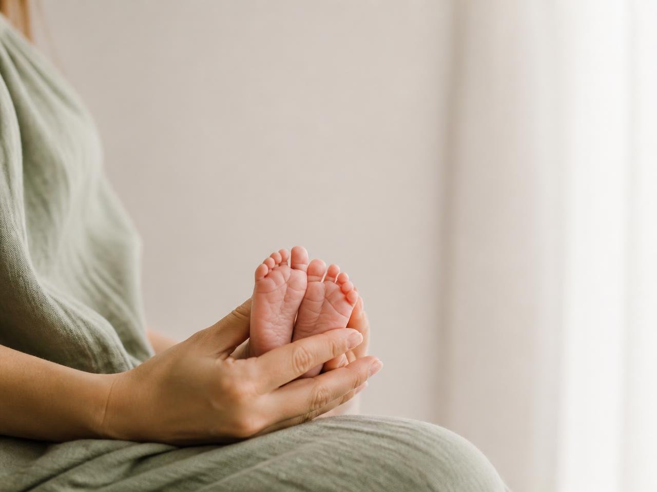 Mãe segurando delicadamente os pés de um bebê